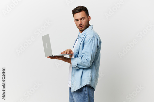 Serious cautious handsome man in casual basic t-shirt sends a secret email with laptop look aside posing isolated on white studio background. Copy space Banner Mockup. Electronics repair IT concept