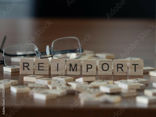 reimport word or concept represented by wooden letter tiles on a wooden table with glasses and a book photo