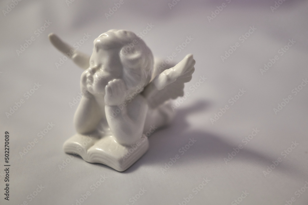 Porcelain angel with a book on a white surface Porcelain angel with a book on a white surface
