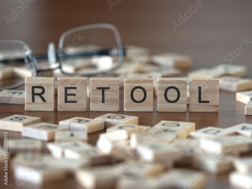 retool word or concept represented by wooden letter tiles on a wooden table with glasses and a book