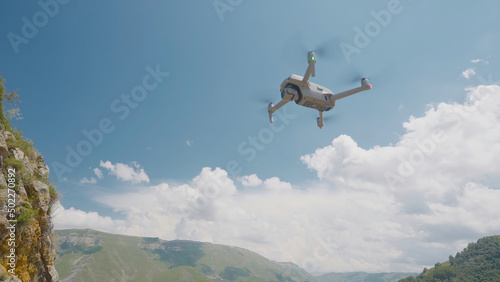 Quadcopter flying on background of mountains and sky. Action. Professional quadcopter for shooting while traveling. Quadcopter rises and takes pictures of mountain landscapes © Media Whale Stock