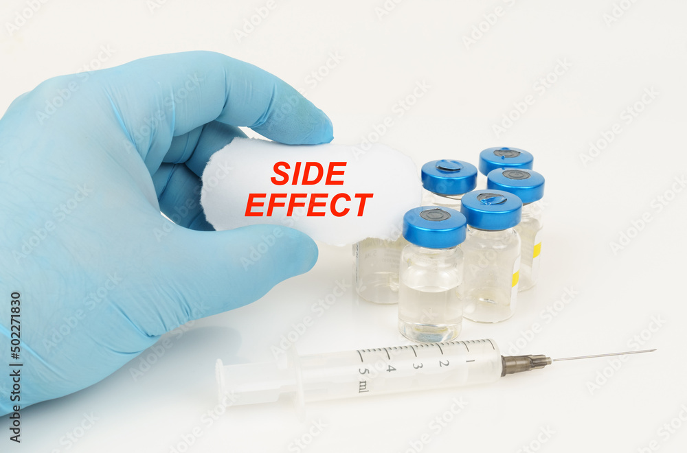 In his hand is a piece of paper with the inscription - SIDE EFFECT, next to it lies a syringe and injection jars. In his hand is a piece of paper with the inscription - SIDE EFFECT, next to it lies a syringe and injection jars.