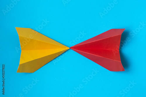 multicolored paper planes on a blue background. The concept of leadership, teamwork and courage.