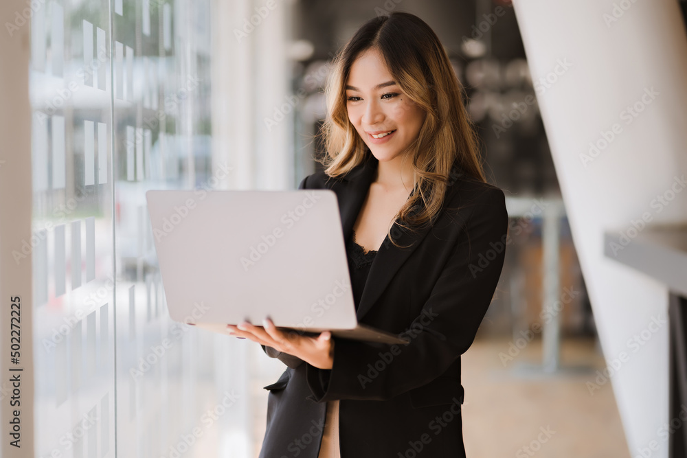 Asian businesswoman in formal suit in office happy and cheerful during using smartphone and working Asian businesswoman in formal suit in office happy and cheerful during using smartphone and working