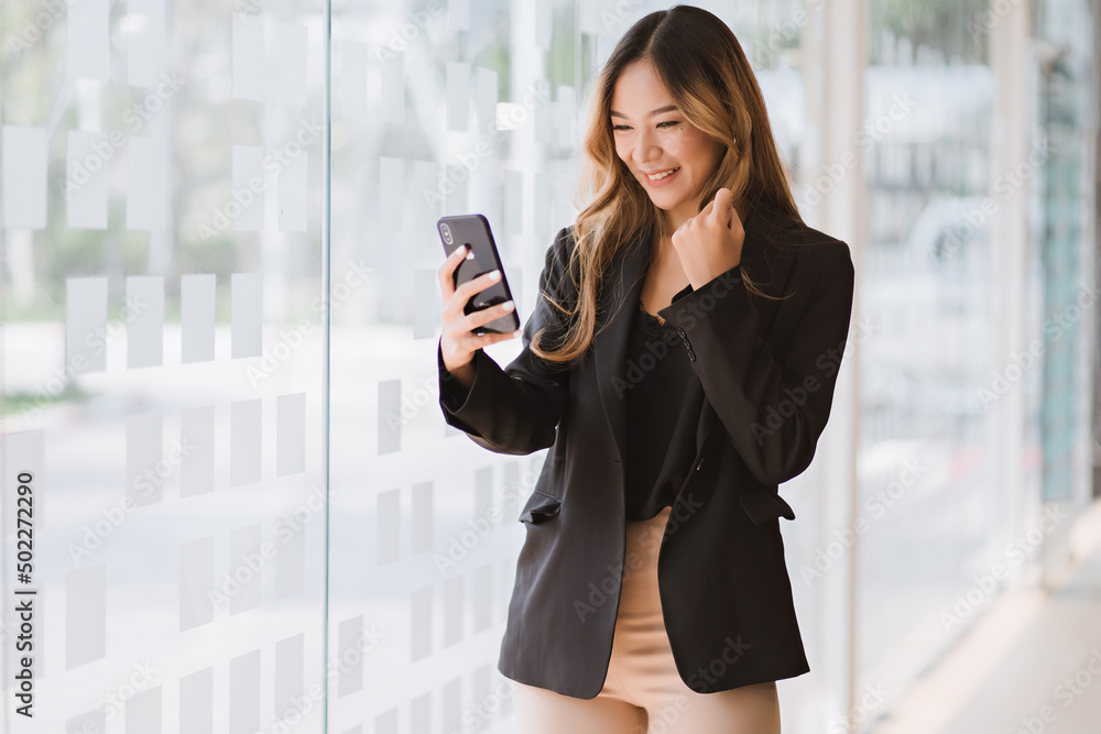 Asian businesswoman in formal suit in office happy and cheerful during using smartphone and working Asian businesswoman in formal suit in office happy and cheerful during using smartphone and working