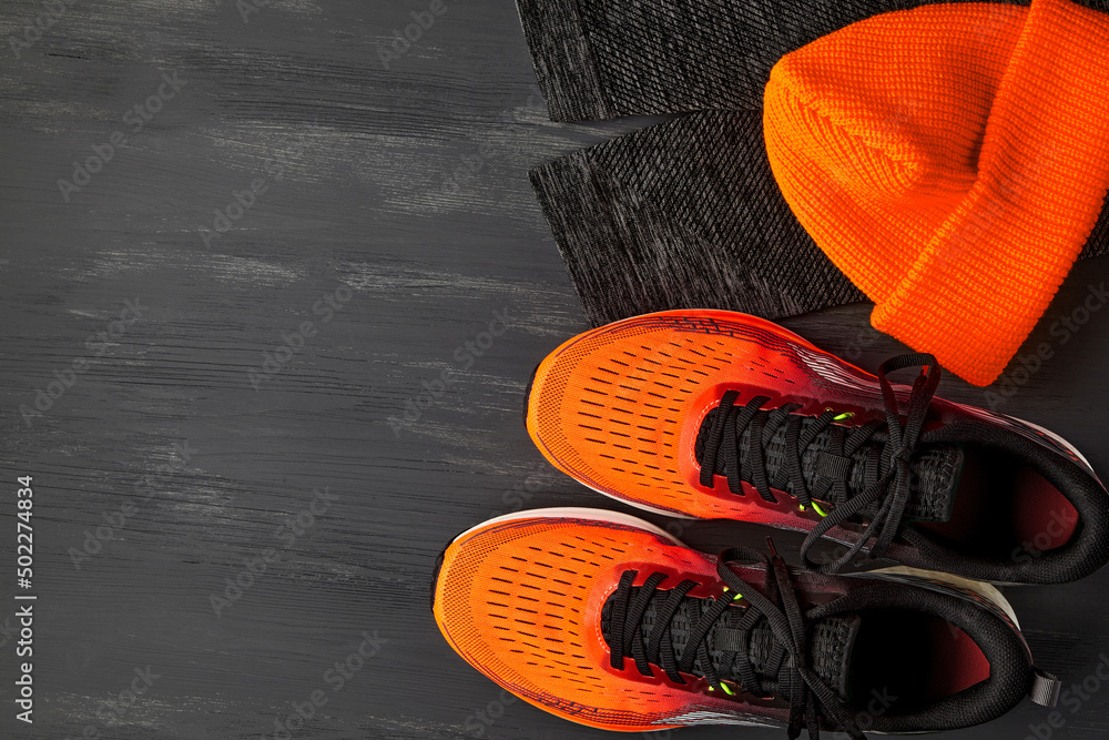 Orange sneakers, orange knitted hat, warm running leggings on a dark wooden  table foto de Stock | Adobe Stock