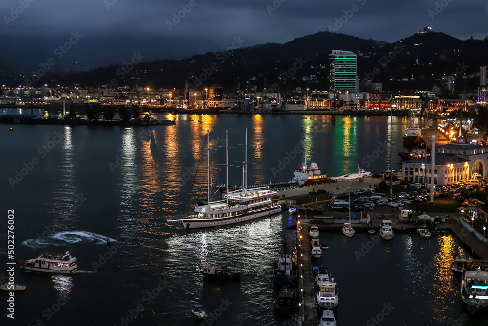 Panoramic view of a large seaport with passenger boats and ships at night.
