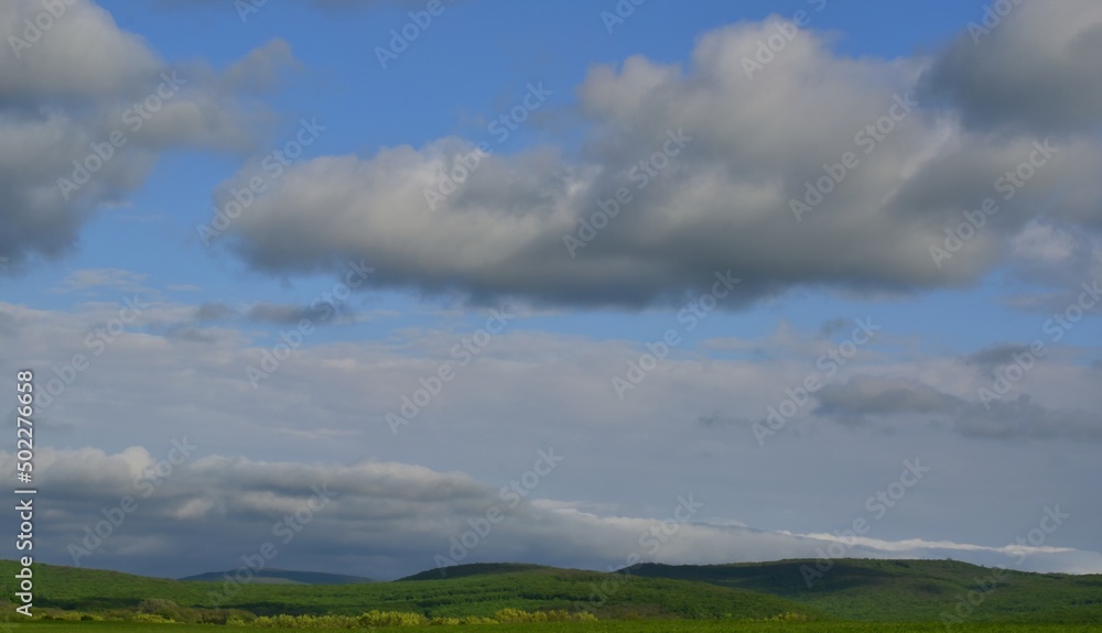 Dense clouds rise above the hills covered with greenery.Sunny day.Spring. Krasnodar region .Russia.