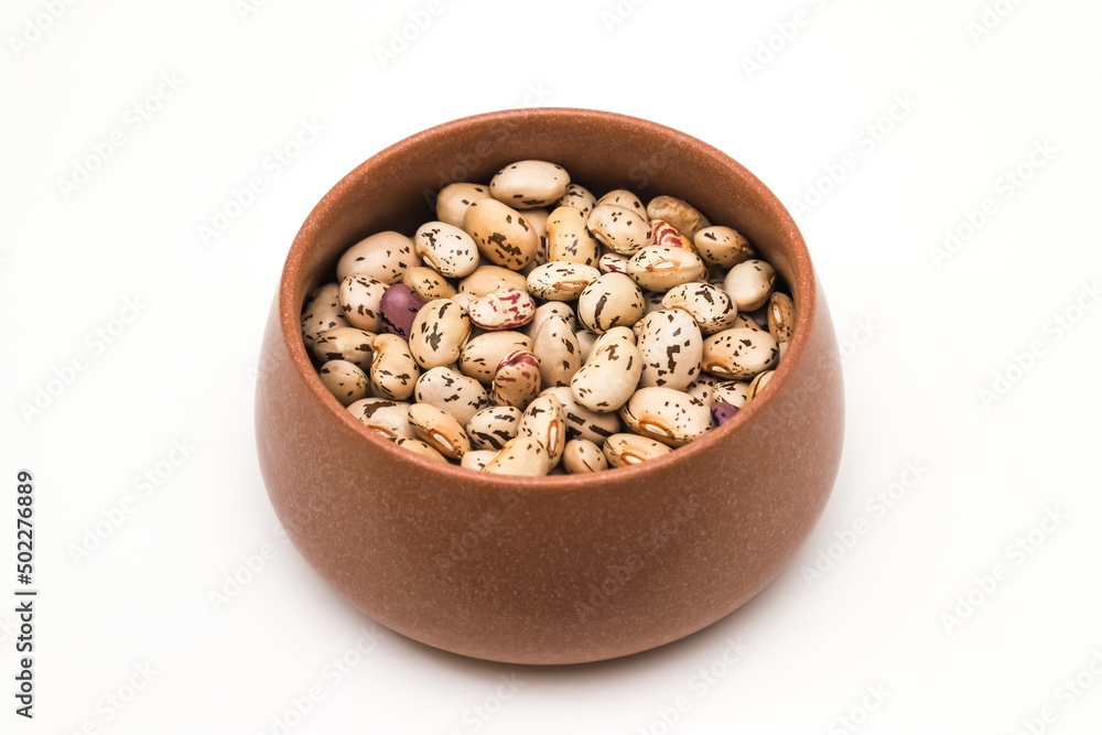 Bean grains in a clay pot on a white background. Close-up