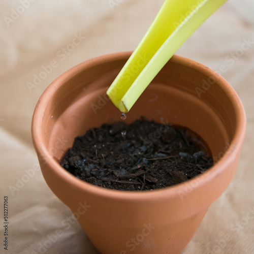 Canvastavla Close up of a clay pot during watering, with a drop falling