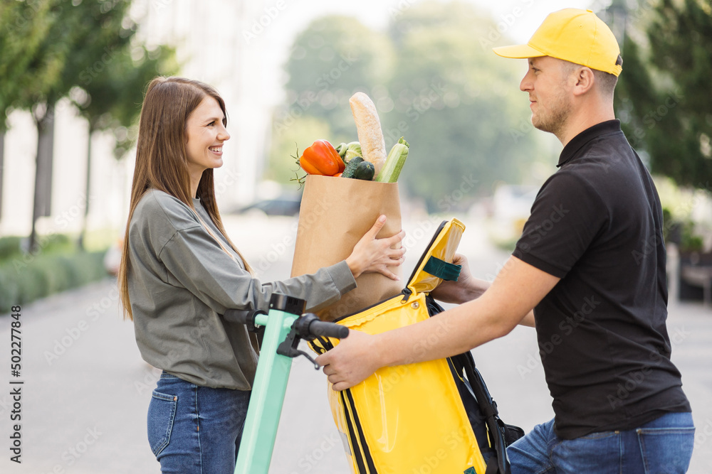 Caucasian man works in delivery service. The girl received the parcel  delivery with organic fresh vegetables