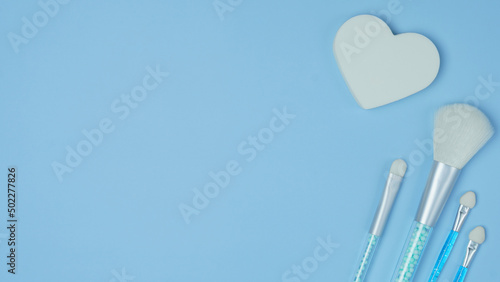 cosmetic accessories on a blue background. makeup brushes  sponges for applying decorative cosmetics close-up. pattern with cosmetics. top view  flat lay.