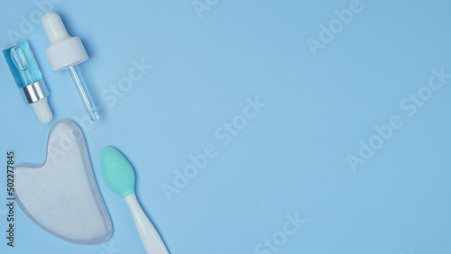 cosmetic accessories on a blue background. facial wash brush, gouache stone facial massager, skin care products close-up. pattern with cosmetics. top view, flat lay.