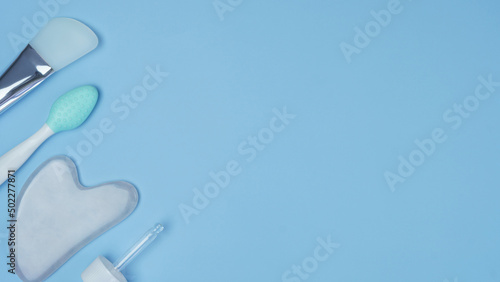 cosmetic accessories on a blue background. facial wash brush, gouache stone facial massager, skin care products close-up. pattern with cosmetics. top view, flat lay.