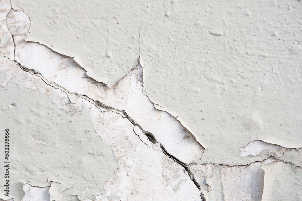 Texture of an old concrete light gray painted wall with cracks close up Texture of an old concrete light gray painted wall with cracks close up