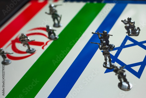 The concept of the economic and political crisis between Israel and Iran, toy soldiers attacking each other against the background of national flags.