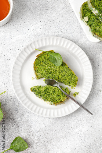 Spinach cake on plate. Piece of Sponge green pie. Grey background. Green cake texture
