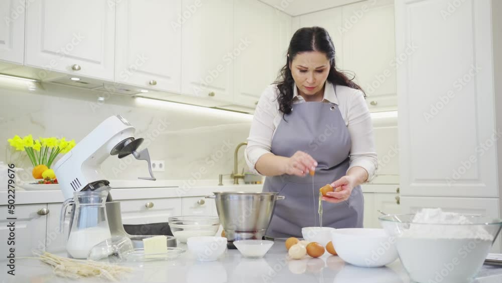 A woman breaks an egg and separates yolks from proteins A woman breaks an egg and separates yolks from proteins