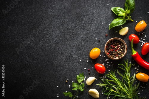 Food cooking background on black stone table. Fresh vegetables, herbs and spices. Ingredients for cooking with copy space.
