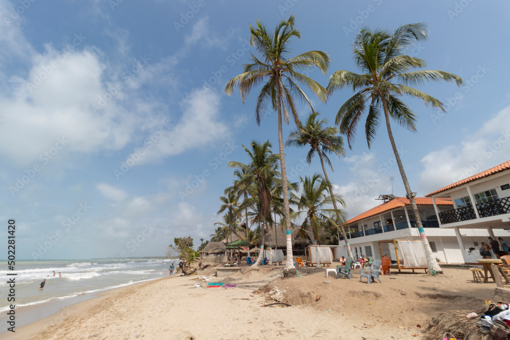 PALOMINO, COLOMBIA - Hostel at the edge of beach with big palms in sunny day