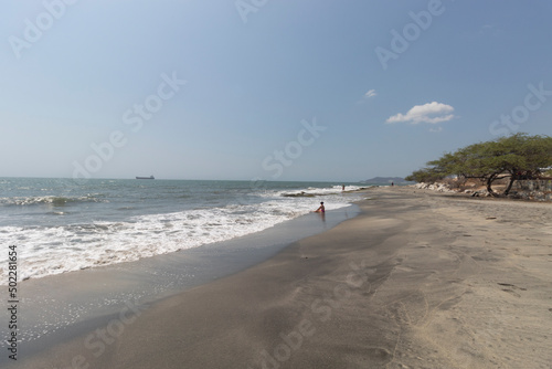 Beautiful landscape of Santa Marta Colombia airport beach with a woman relaxing a big ship and city at background at midday