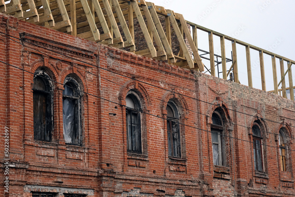 reconstruction of the building after a fire. red brick building with charred windows and roof boards. the building is being restored after a fire inside. reconstruction of the building after a fire. red brick building with charred windows and roof boards. the building is being restored after a fire inside.