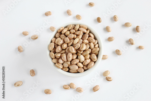 Carioca beans bowl with grains scattered on the white surface.