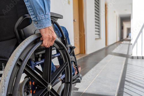 MAN WITH PHYSICAL DISABILITY USING A WHEELCHAIR IN A CORRIDOR. CONCEPTUAL IMAGE OF INCLUSION, INTEGRATION FOR PEOPLE WITH DISABILITIES AND REMOVE BARRIERS. photo
