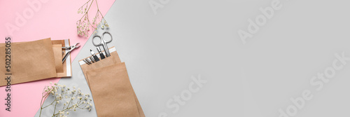 Paper bags with manicure instruments and flowers on pink and grey background with space for text