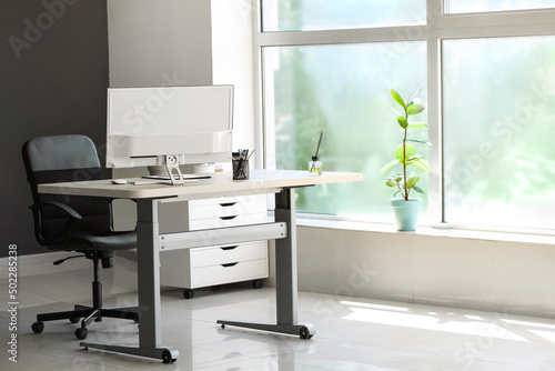 Standing desk with modern computer and chair in office photo