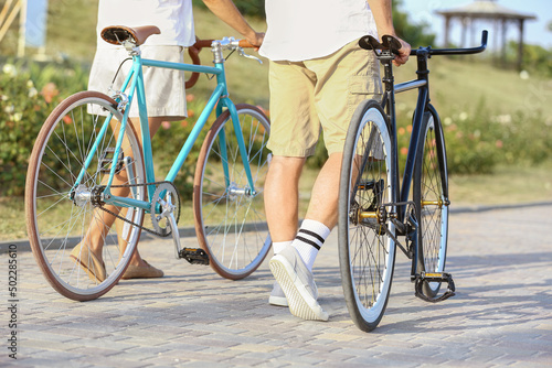 Mature couple with bicycles walking in city park on summer day