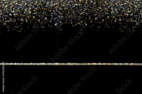 Black background with gold and silver sparkles. Stylish festive dark background copy space and glowing bokeh. Gold glitter defocused abstract Twinkly Lights Background. © NikonLamp
