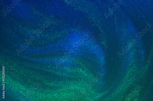 Abstract wavy overflows of liquid with glitter of blur and green colors. Abstract fluid background with swirl pattern, beauty gel and cosmetic texture illuminated with neon lights.