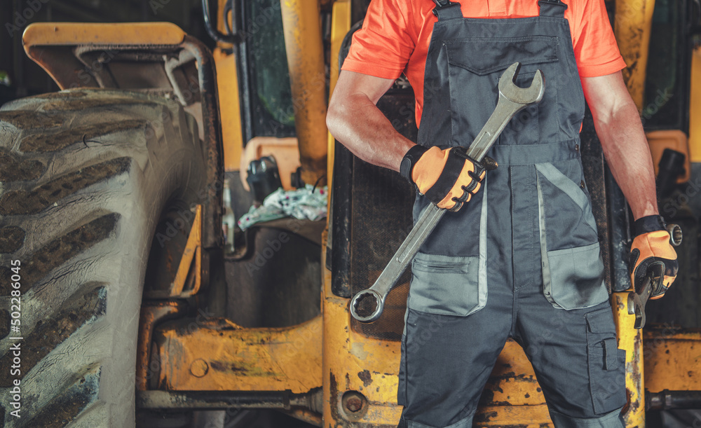 Heavy Construction Equipment Mechanic with Large Wrench in His Hand Heavy Construction Equipment Mechanic with Large Wrench in His Hand