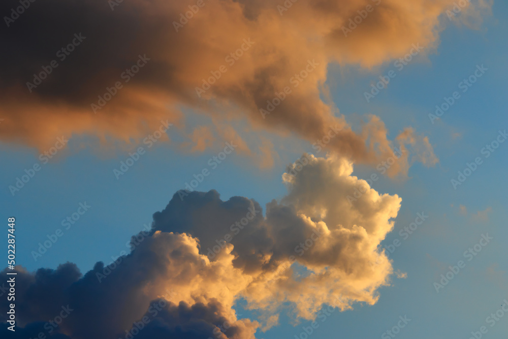 clouds shaded in various shades of orange, blown by the winds under the twilight sky.