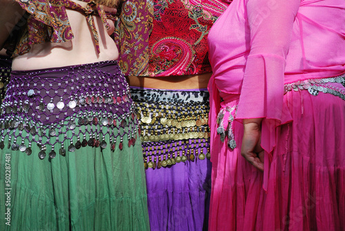 Bellydancers in colorful costumes on stage outdoors.