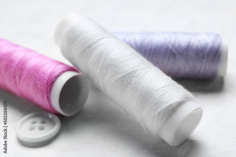 Sewing threads on light wooden background, closeup Sewing threads on light wooden background, closeup