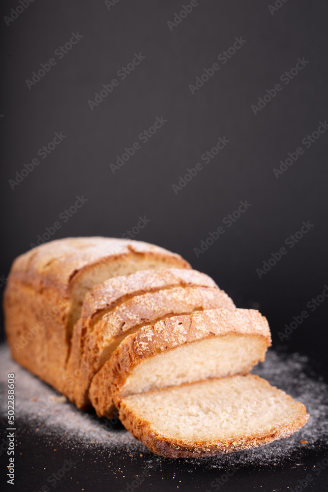 close up sliced french lean bread with flour on a black background. Concept recipe of handmade bread