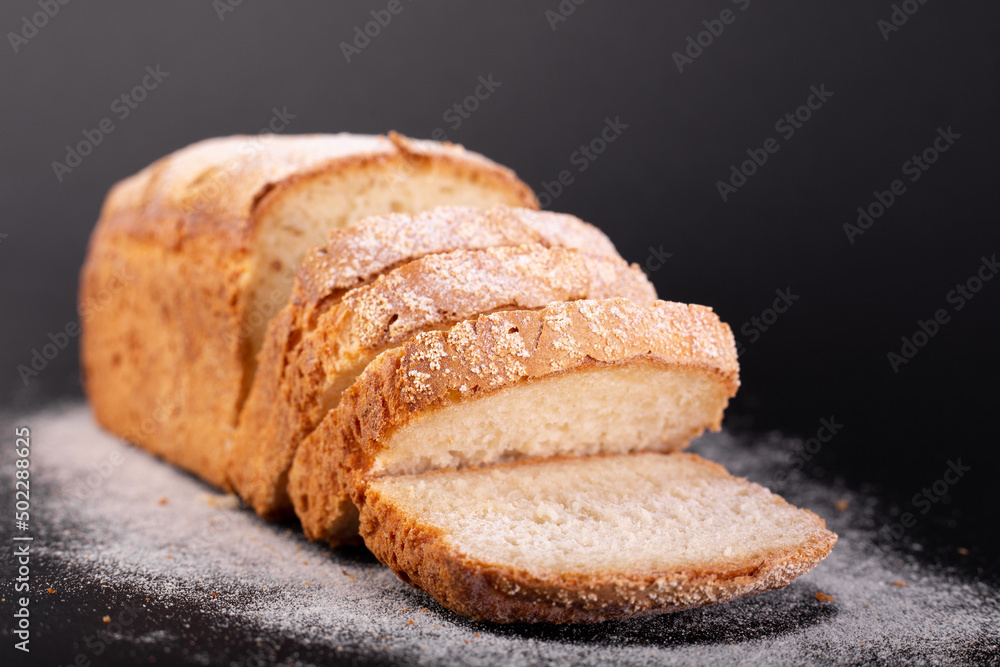 close up sliced french lean bread with flour on a black background. Concept recipe of handmade bread close up sliced french lean bread with flour on a black background. Concept recipe of handmade bread