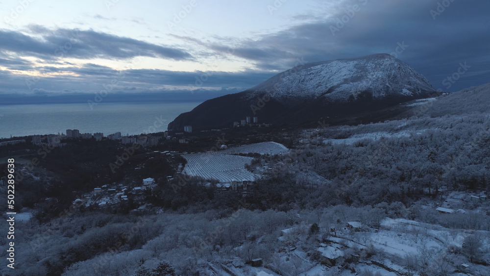 Top view of the city near the sea in winter. Shot. Snowy expanses in the mountainous area near the city