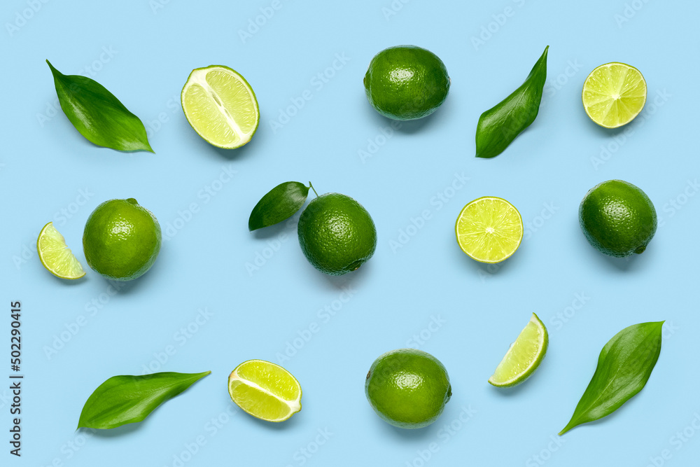Composition with juicy limes and leaves on blue background Composition with juicy limes and leaves on blue background