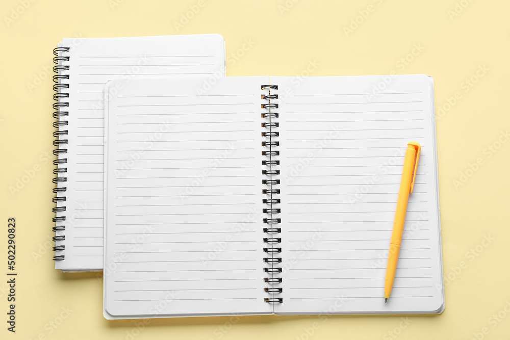 Notebooks and pen on light yellow background Notebooks and pen on light yellow background