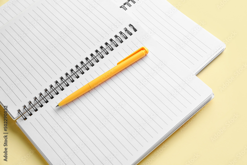 Notebooks and pen on light yellow background Notebooks and pen on light yellow background
