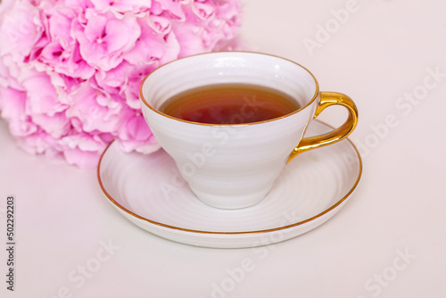 Cup of tea and pink hydrangea on white table