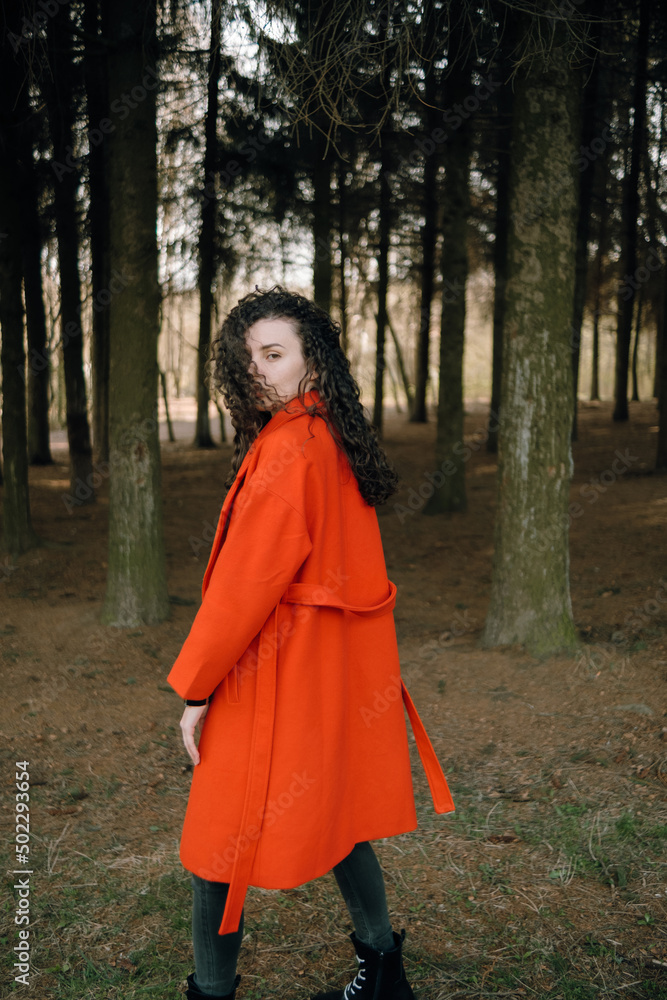portrait of curly brunette woman in red coat in the park portrait of curly brunette woman in red coat in the park