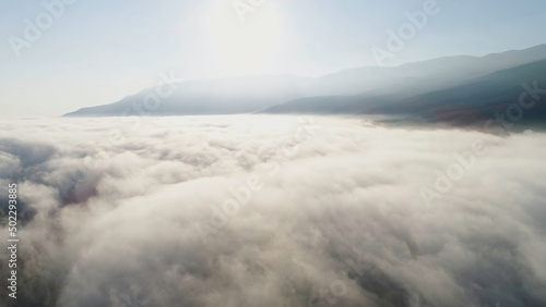 Fototapeta Naklejka Na Ścianę i Meble -  Aerial view of clouds and landscape under them. Shot. Top view of the clouds under the sky. Under the clouds shot from a bird's flight, the sun shines on the clouds