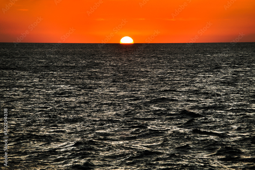 Sunset sunrise over ocean sea rising setting sun red