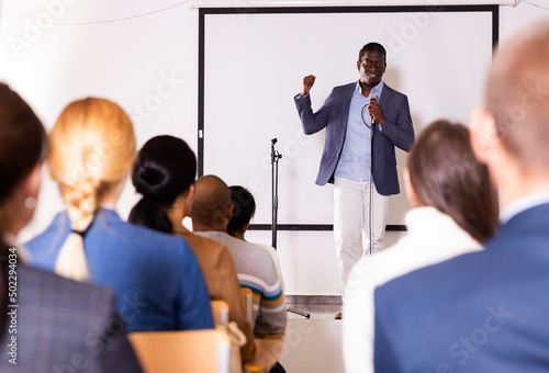 Portrait of confident successful man giving motivation training at conference hall