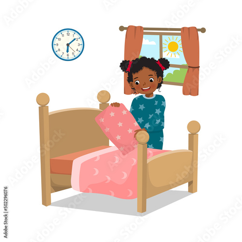 cute little African girl making bed arranging pillow and bed cover neat doing her housework chores in the morning at home
