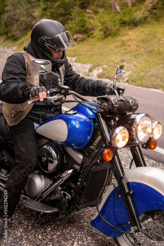 Guy riding retro cruiser motorcycle on mountain road in South tyrol